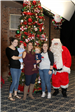 family smiling for photo with Santa